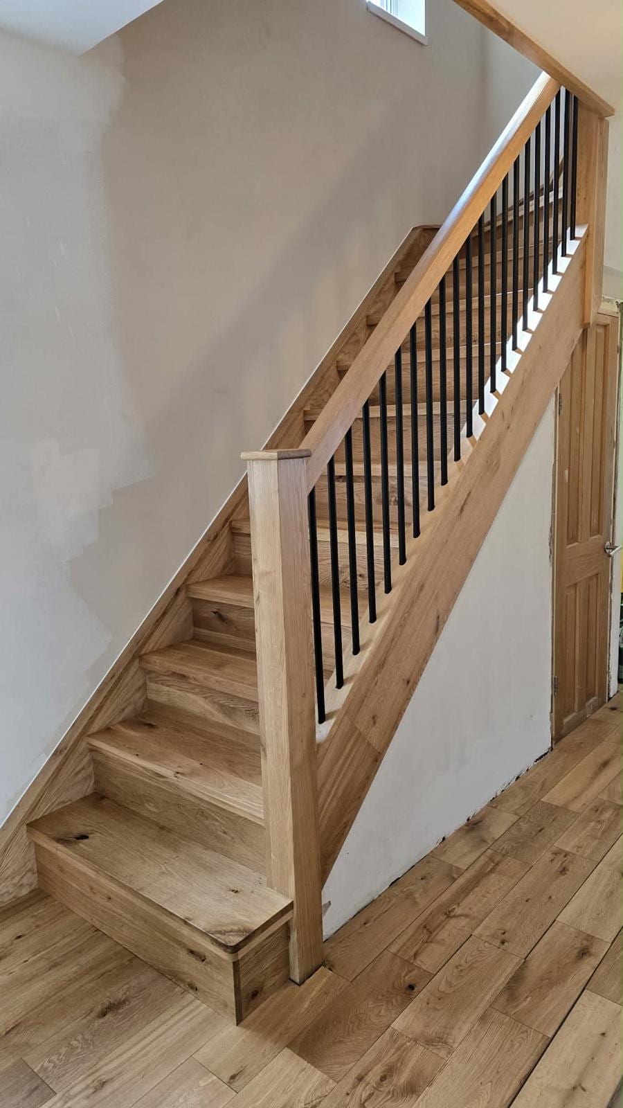 Black spindle balustrade with solid oak handrail on a finished staircase