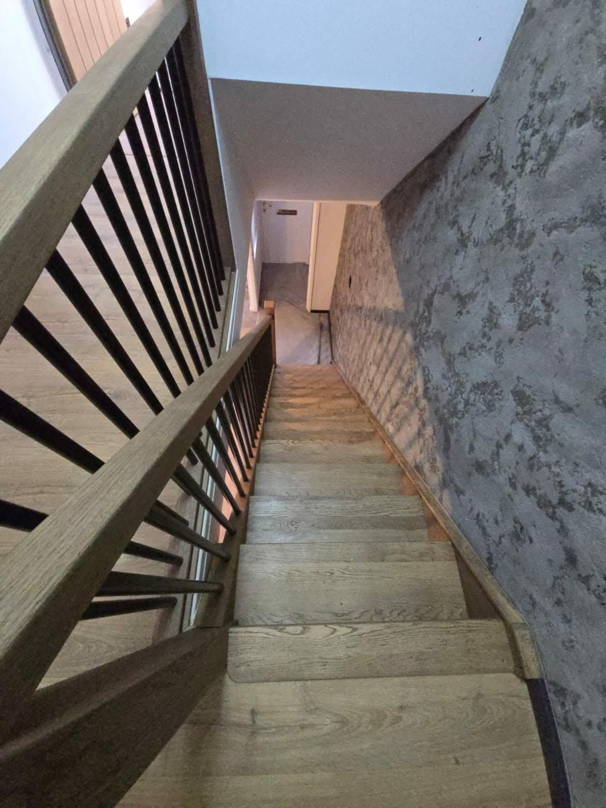 Oak handrail and black metal spindle balustrade running down a staircase
