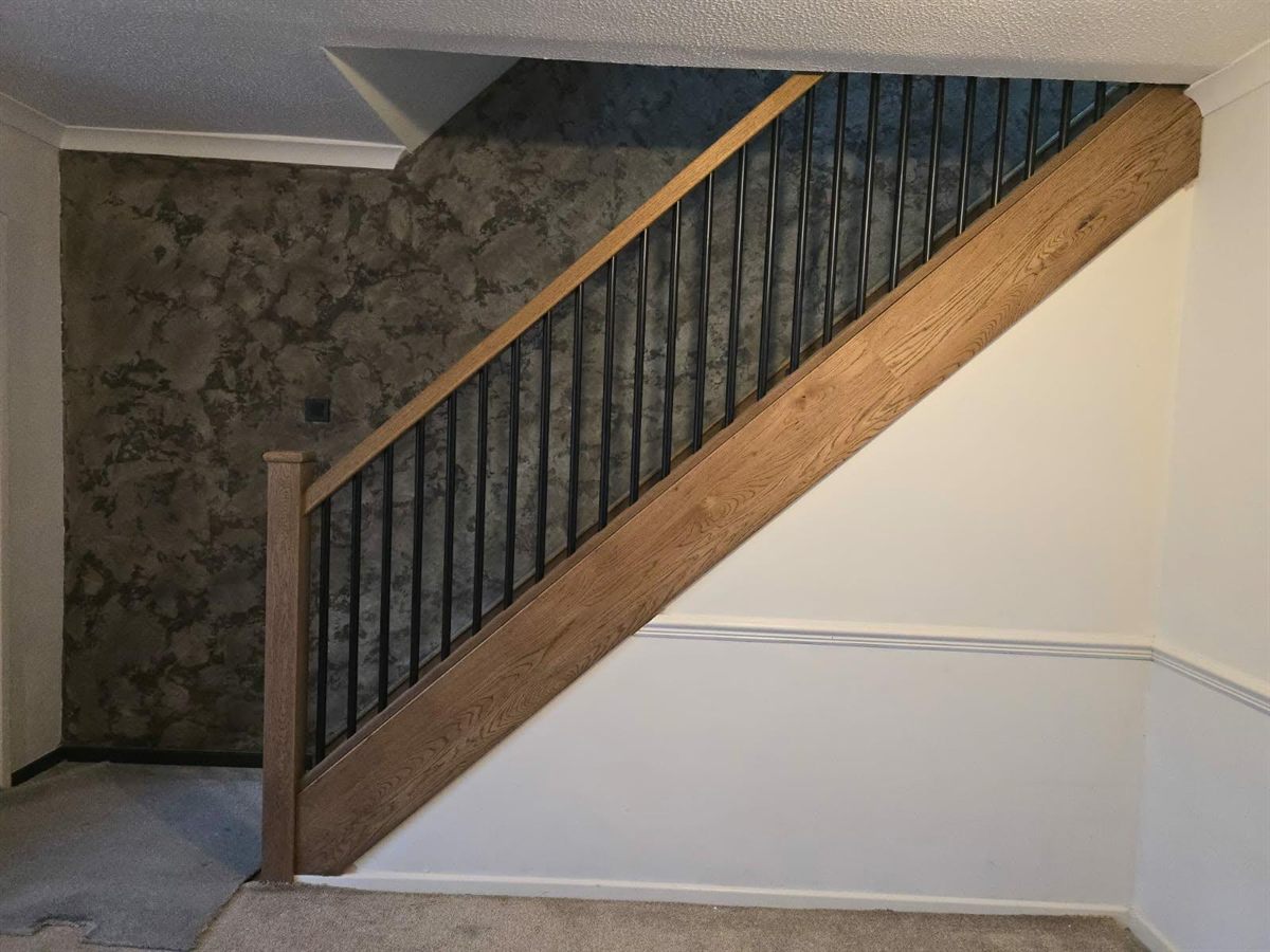 Full side profile of an oak balustrade and staircase against a feature wall
