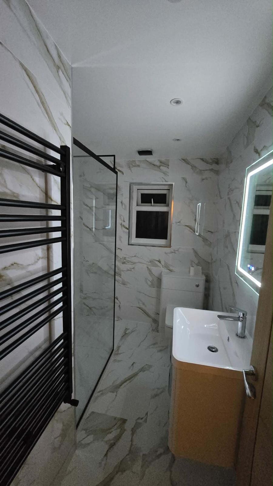 Full bathroom fit-out with a marble-effect tiled shower enclosure