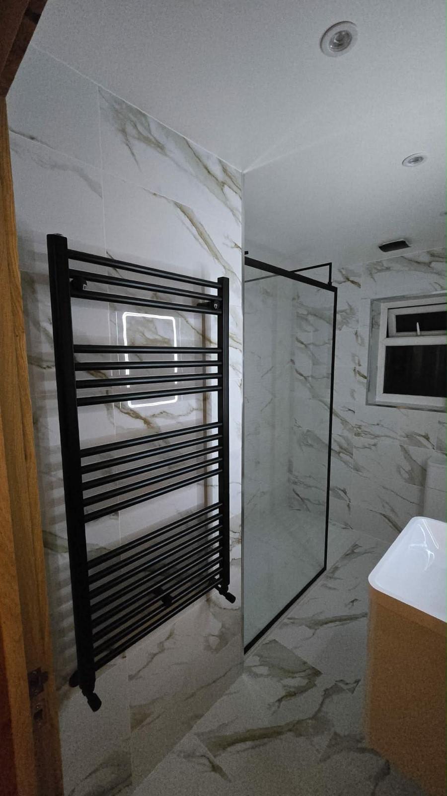 Bathroom fit-out with marble-effect tiling and illuminated mirror