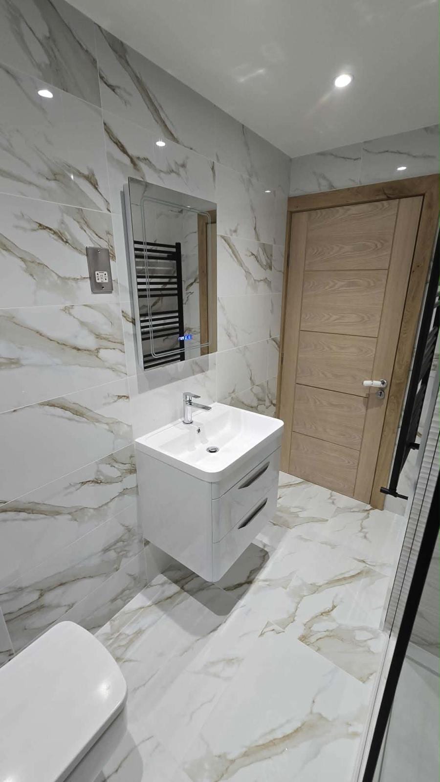 Bathroom fit-out with fitted vanity unit, mirror and marble-effect tiling