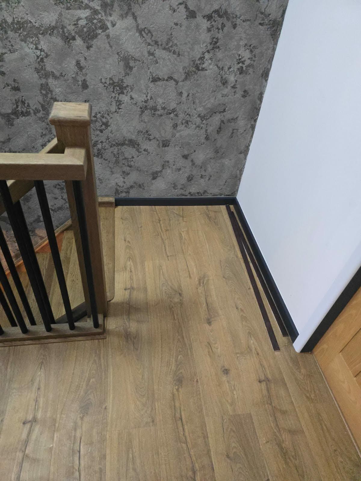 Close-up of oak-effect flooring with a fitted threshold trim against the skirting