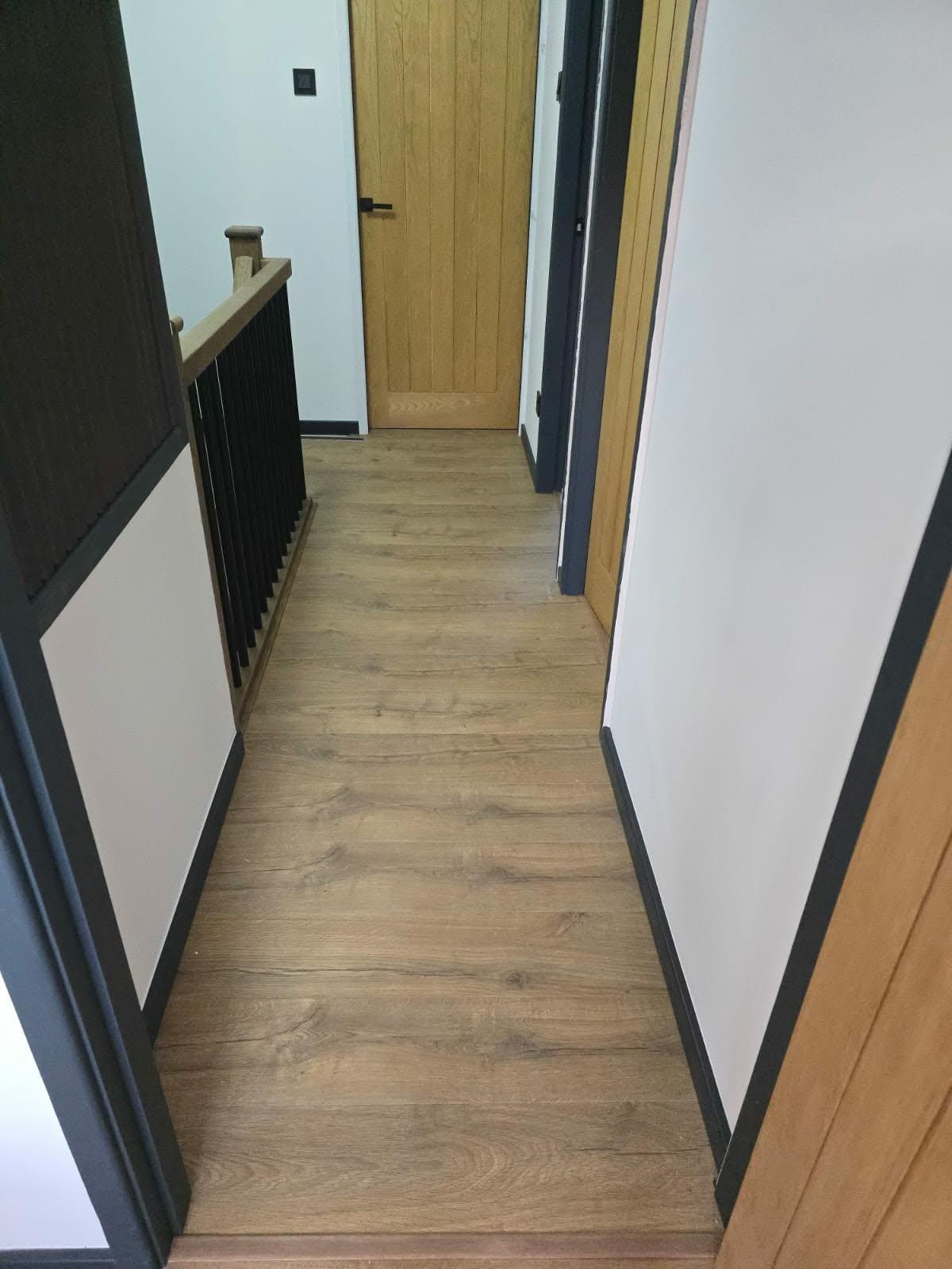 Oak-effect flooring fitted along a hallway leading to bedroom doors