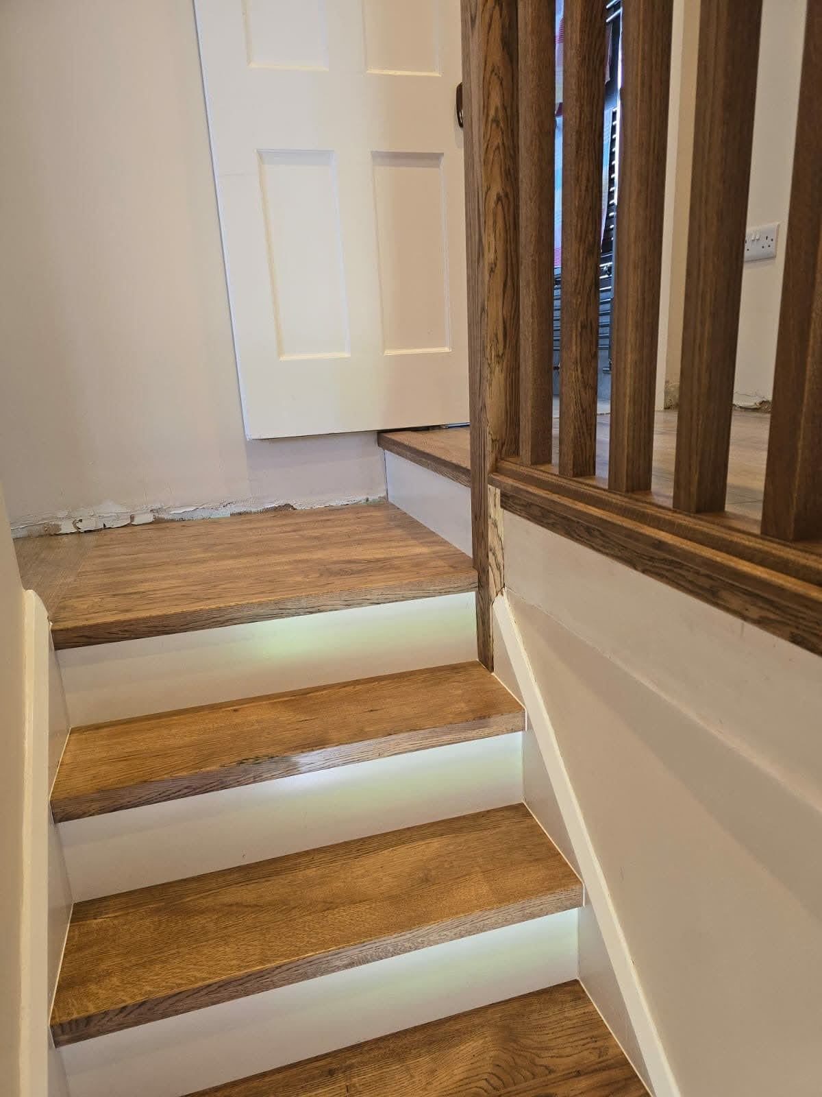 Oak stair overlay viewed from the landing, black spindles and oak handrail
