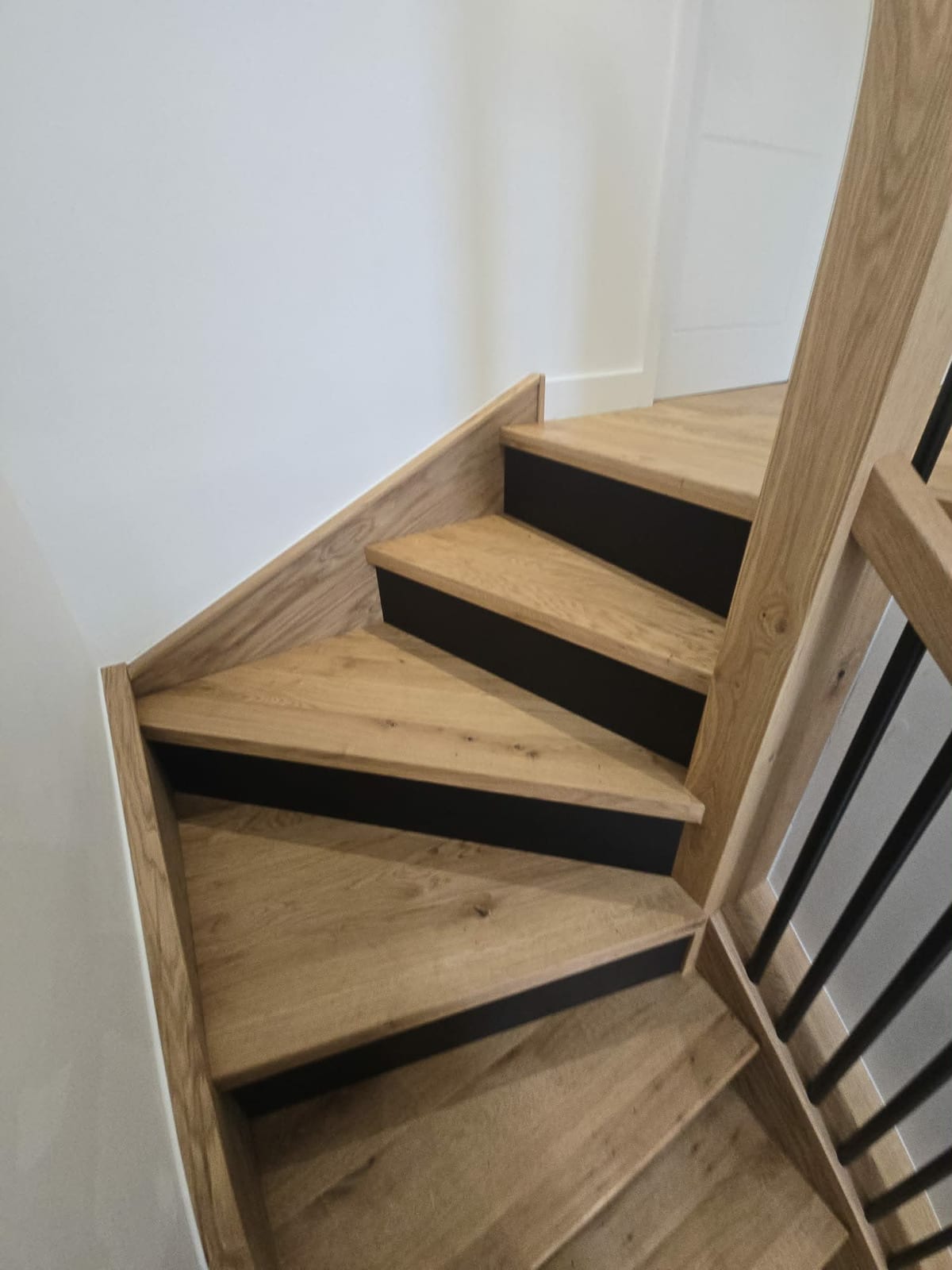 Solid oak stair overlay with black metal spindles fitted over an existing staircase