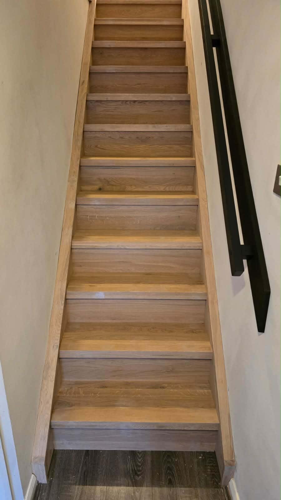 Oak stair overlay viewed from the landing, black spindles and oak handrail