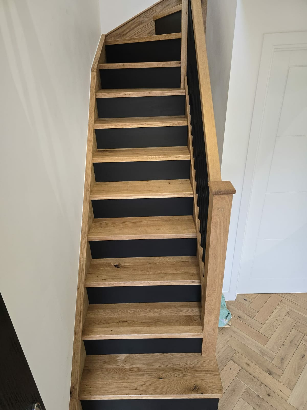 Solid oak stair overlay with black metal spindles fitted over an existing staircase