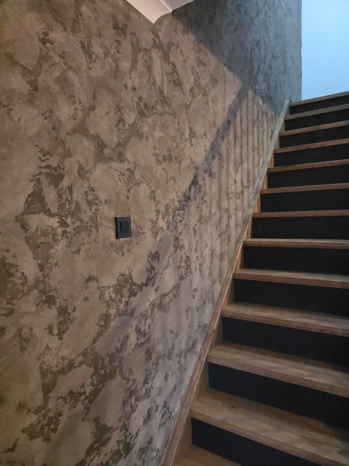 Oak stair string board and treads viewed alongside a textured feature wall