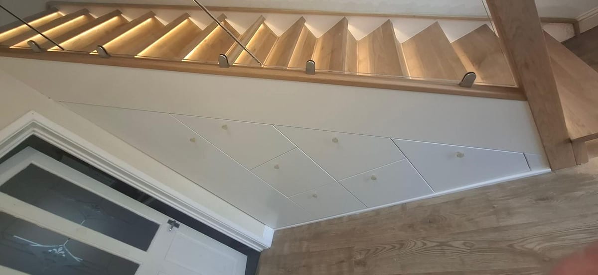 Under-stair storage with oak-topped drawer fronts and integrated stair lighting